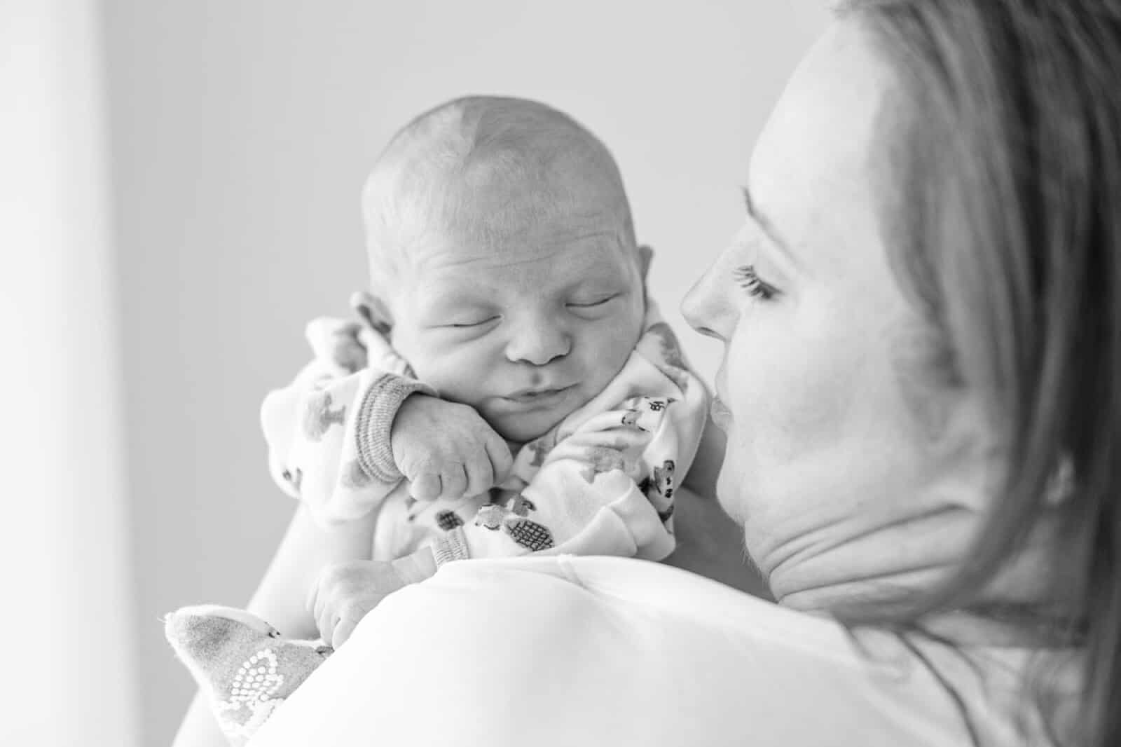 mother holds newborn baby at her shoulder